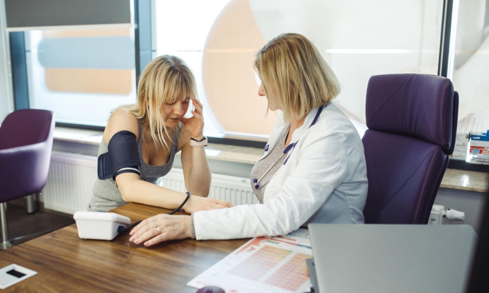 Doctor treating patient for high blood pressure and headache symptoms in clinic